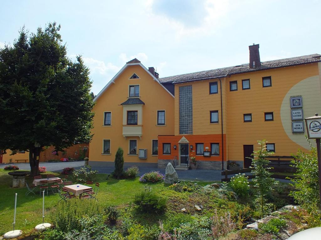 un gran edificio amarillo con un jardín delante de él en Landgasthof Zur Mühle, en Naila