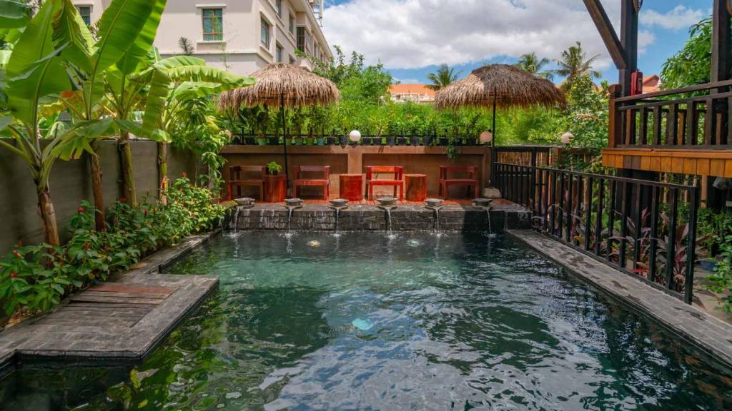 a swimming pool in a backyard with a house at Mango Kesararam in Siem Reap