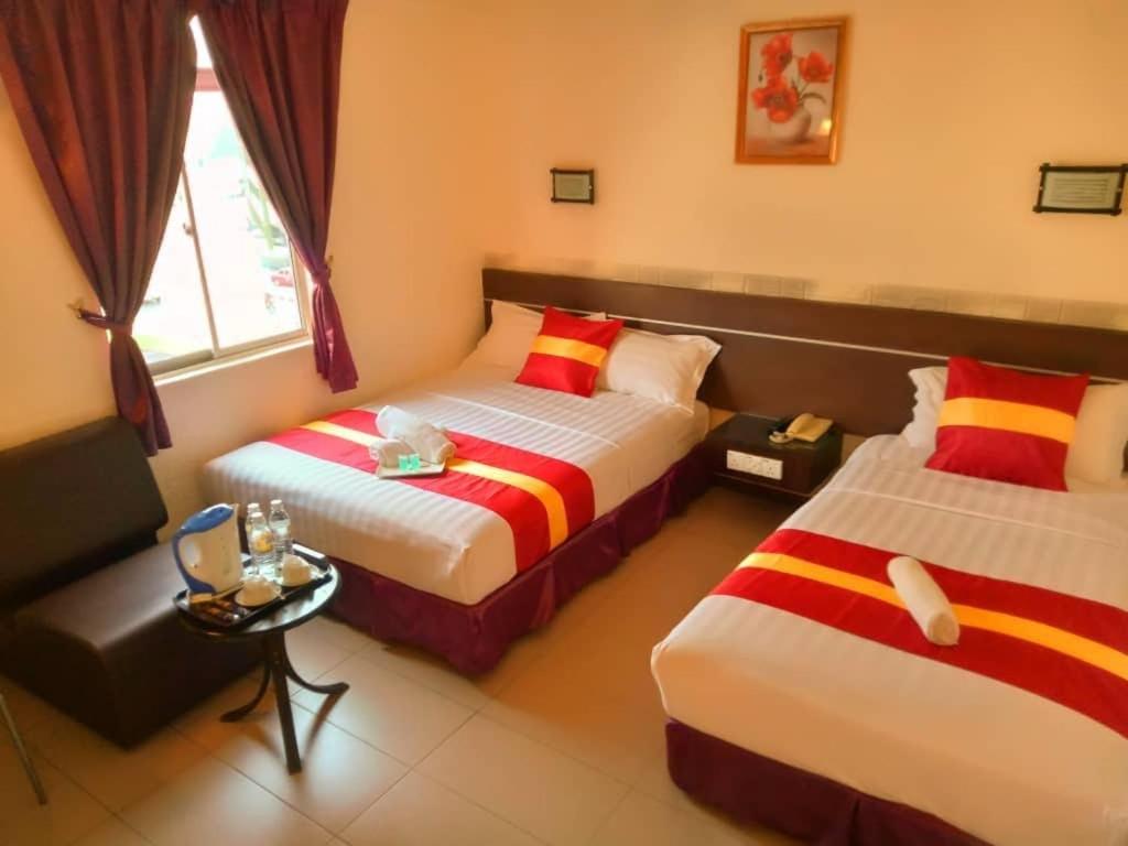 ein Hotelzimmer mit 2 Betten und einem Tisch in der Unterkunft City Inn in Kuching