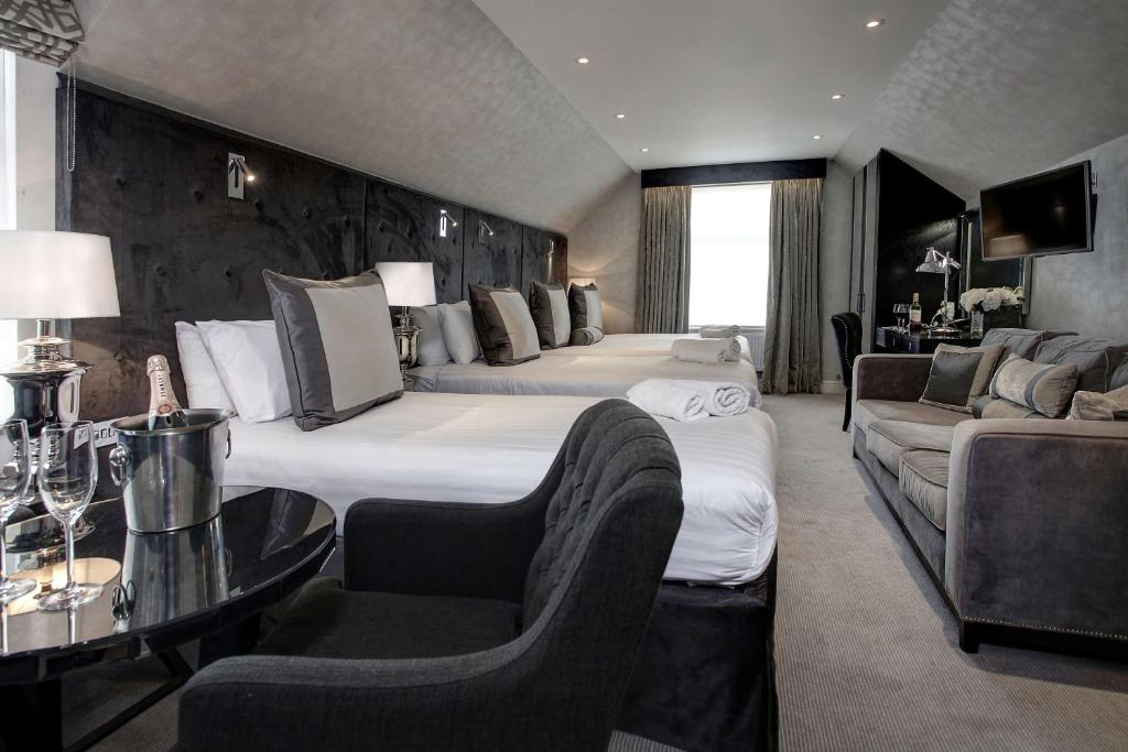 een grote hotelkamer met 2 bedden en een bank bij Best Western Chiswick Palace & Suites London in Londen