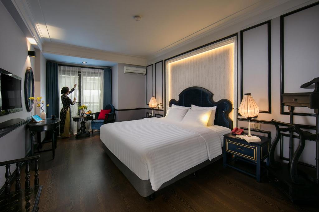 una mujer tomando una foto de una cama en una habitación de hotel en La Beaute Boutique Hotel & Spa, en Hanói