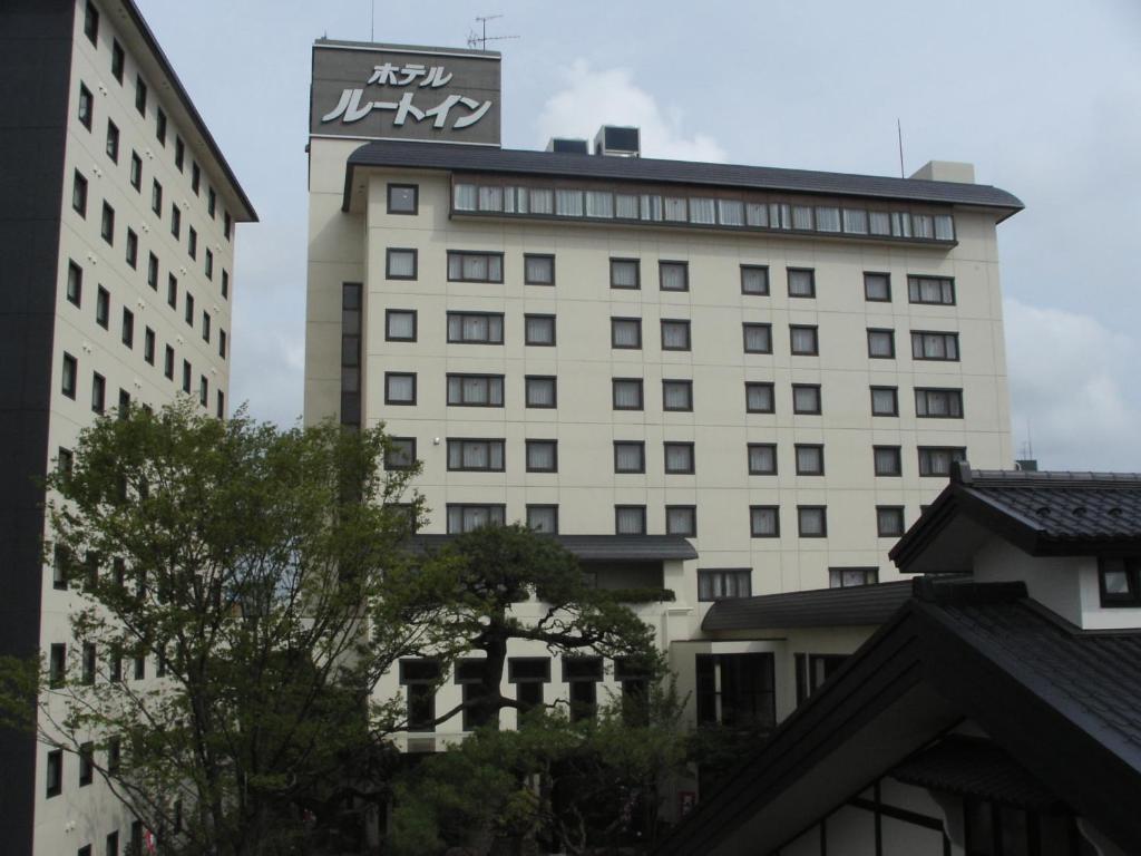 Un grand bâtiment blanc avec un panneau en haut dans l'établissement Route Inn Grantia Akita Spa Resort, à Akita