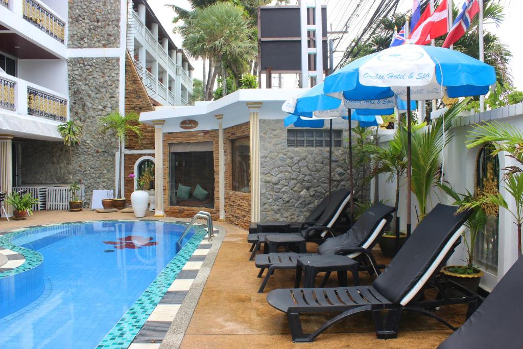 ein Pool mit Stühlen und Sonnenschirmen neben einem Gebäude in der Unterkunft Orchid Hotel and Spa Kalim Bay in Patong Beach