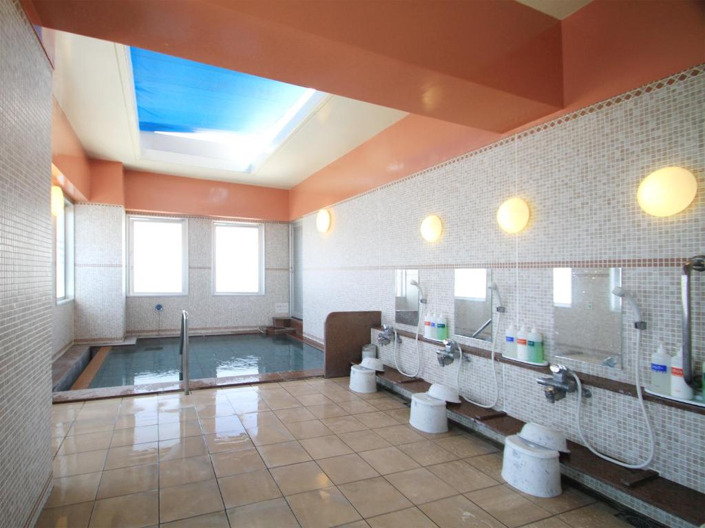 a bathroom with a swimming pool and three toilets at Hotel Route-Inn Nahatomariko in Naha