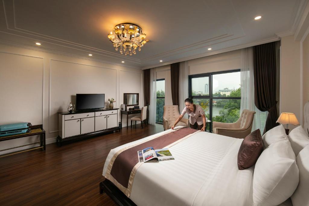 a man in a hotel room with a large bed at Adonis Hotel in Hanoi