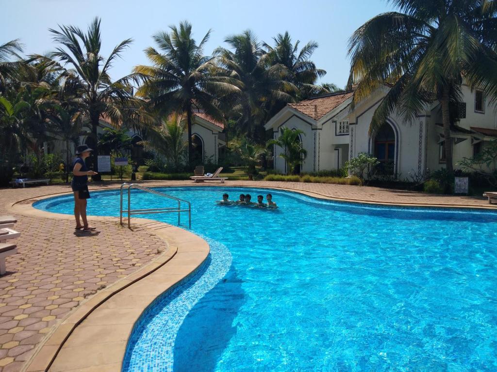 Ein Mann steht vor einem Schwimmbad. in der Unterkunft Casa Legend Villa & Apartments Arpora - Baga - Goa in Baga