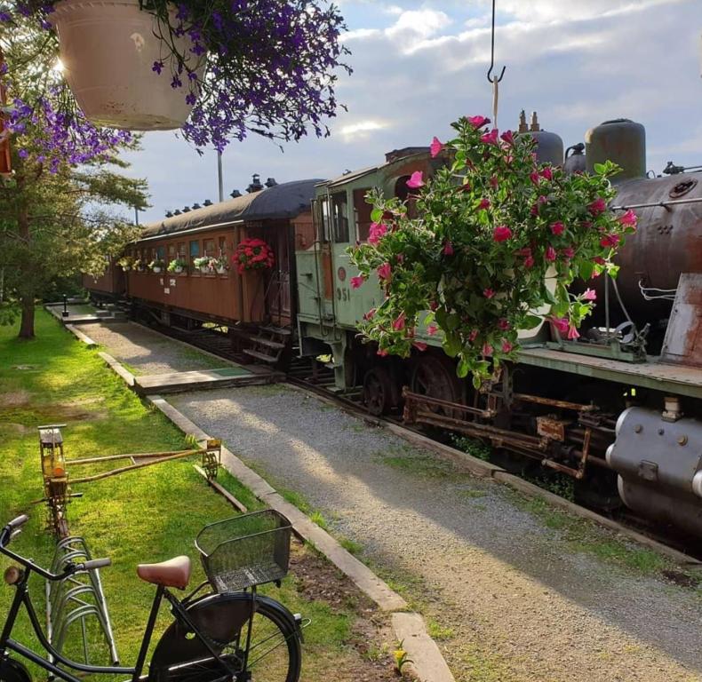 朵利的住宿－Junamajoitus Tuuri Train Station，一辆自行车停在火车旁边,上面放着鲜花