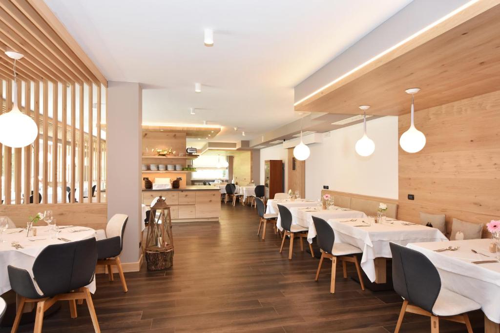 a dining room with white tables and chairs at X Alp Hotel in Pozza di Fassa