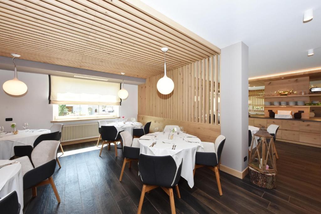 a dining room with white tables and chairs at X Alp Hotel in Pozza di Fassa