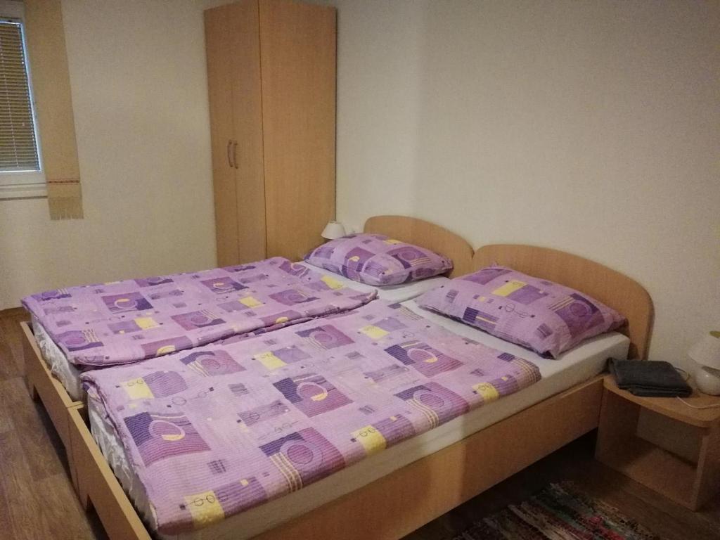 een bed met een paars dekbed en kussens in een slaapkamer bij Apartment House Papa in Vinica