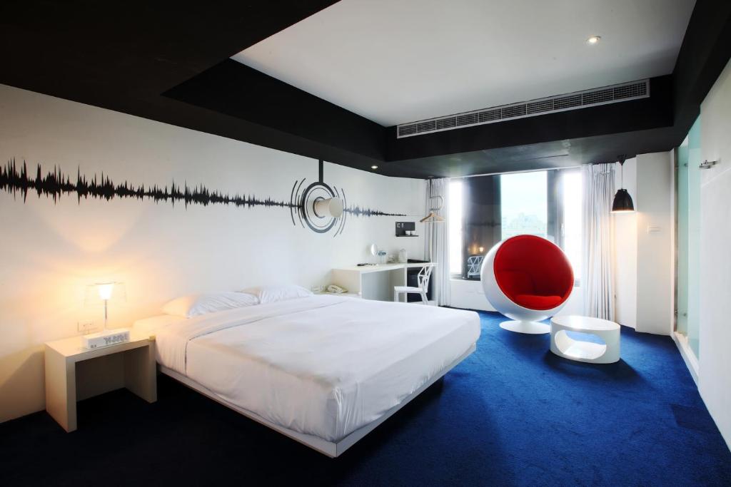 a bedroom with a large bed and a red chair at Hotel Papa Whale-Kaohsiung Formosa Boulevard in Kaohsiung