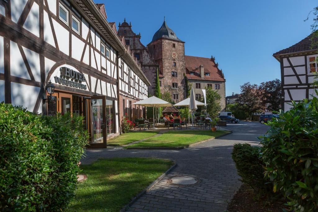 ein Gebäude mit einem Tisch und Sonnenschirmen auf einer Straße in der Unterkunft Hotel Vorderburg in Schlitz