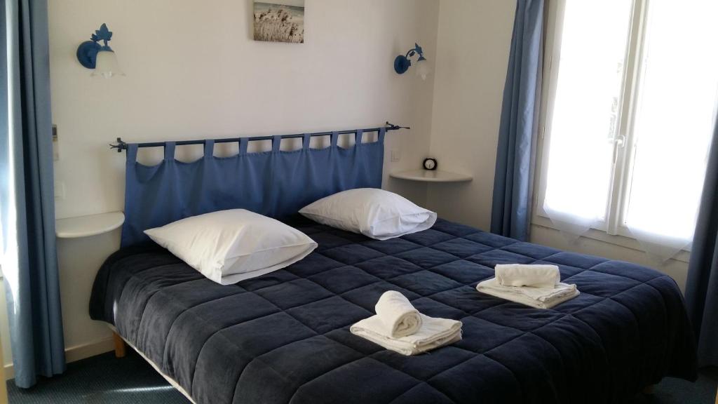 a bedroom with a blue bed with towels on it at Le Concept Hotel in Les Portes