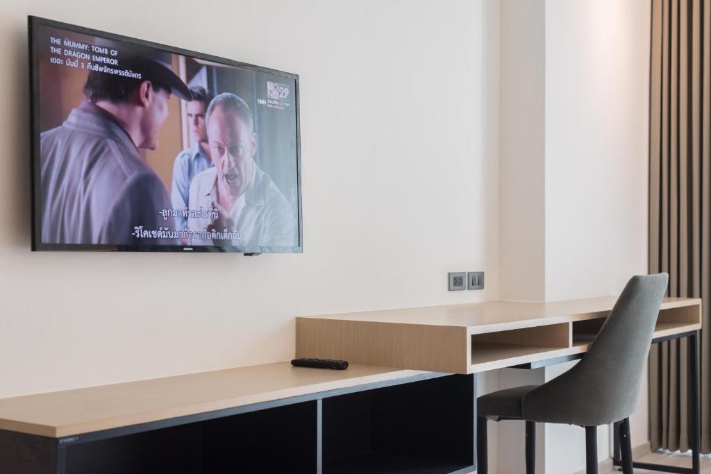 A compact work-and-media wall with a television, desk, chair and low storage.