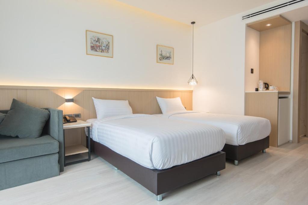 A twin room showing two beds, a sofa and a built-in refreshment area.