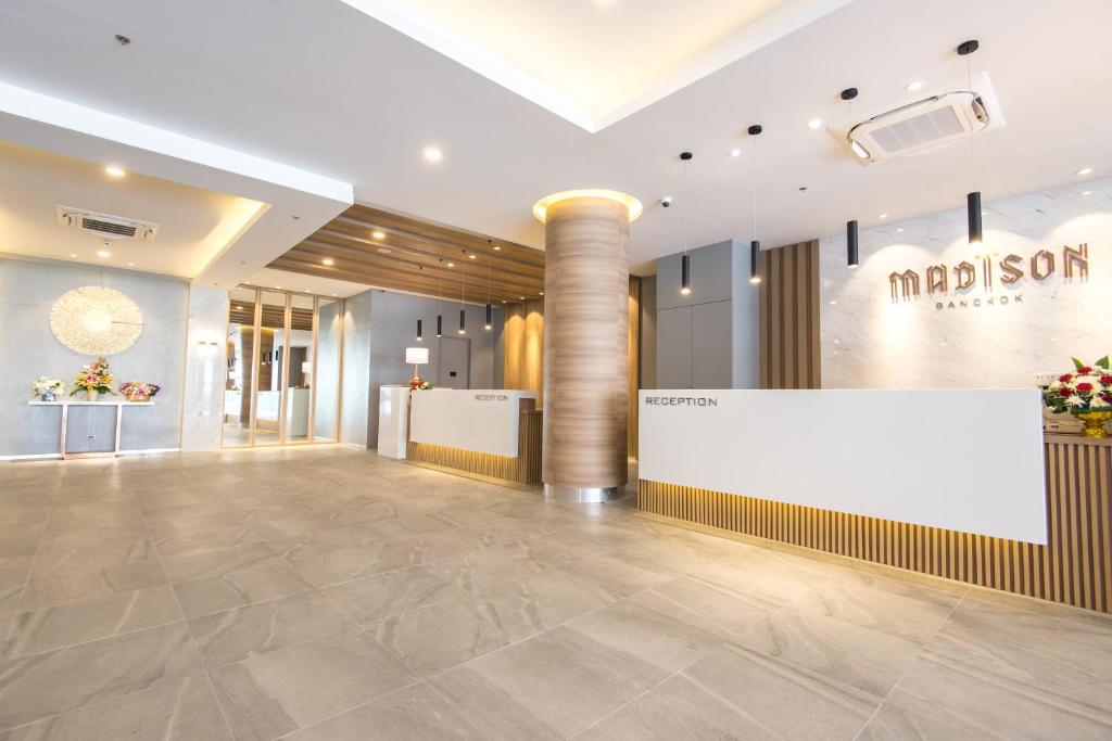 A wide view of a bright modern lobby with reception, seating and polished stone-look flooring.