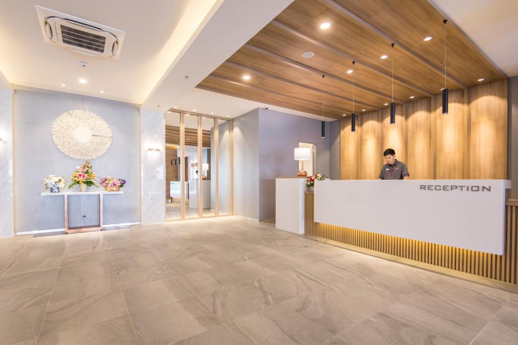 A contemporary reception lobby with a wood-paneled front desk and floral display.