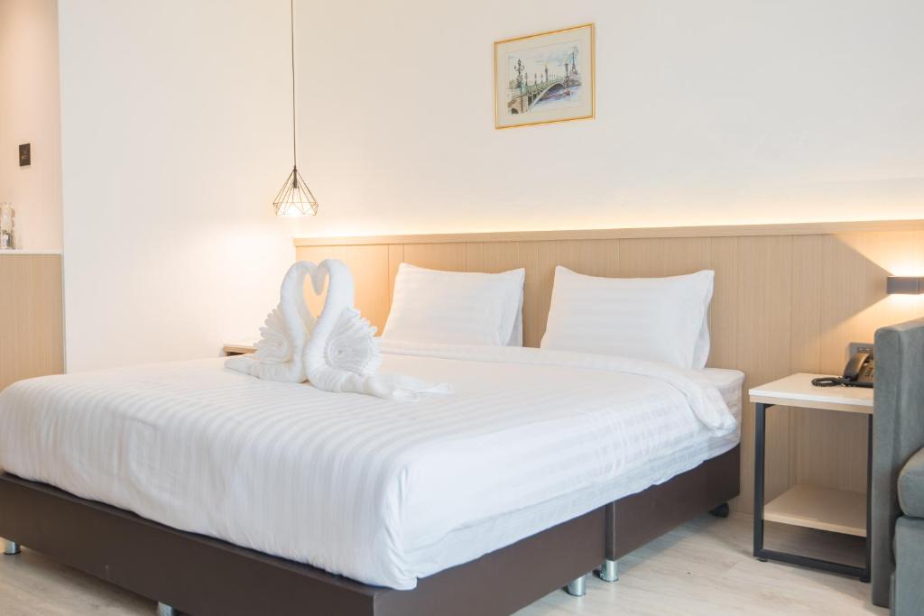 A king bed with decorative towel swans and bedside amenities.