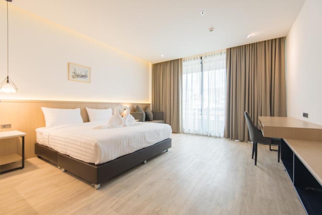 A spacious bedroom with a large bed, window, sofa and long desk.