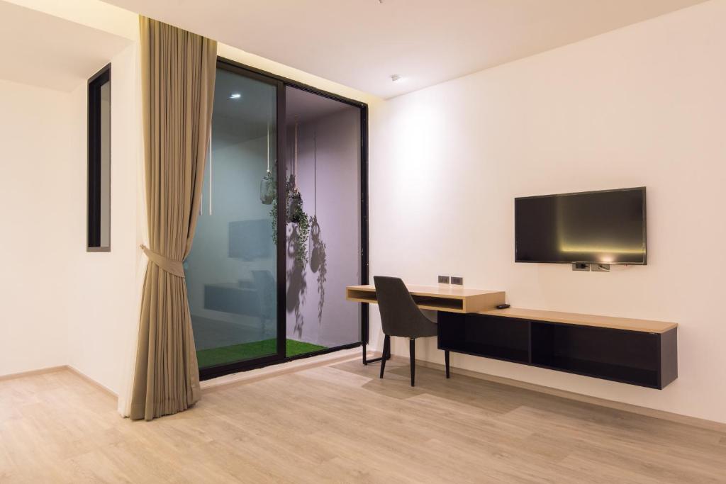 A bedroom workspace with a desk, chair, wall-mounted television and glazed doors.