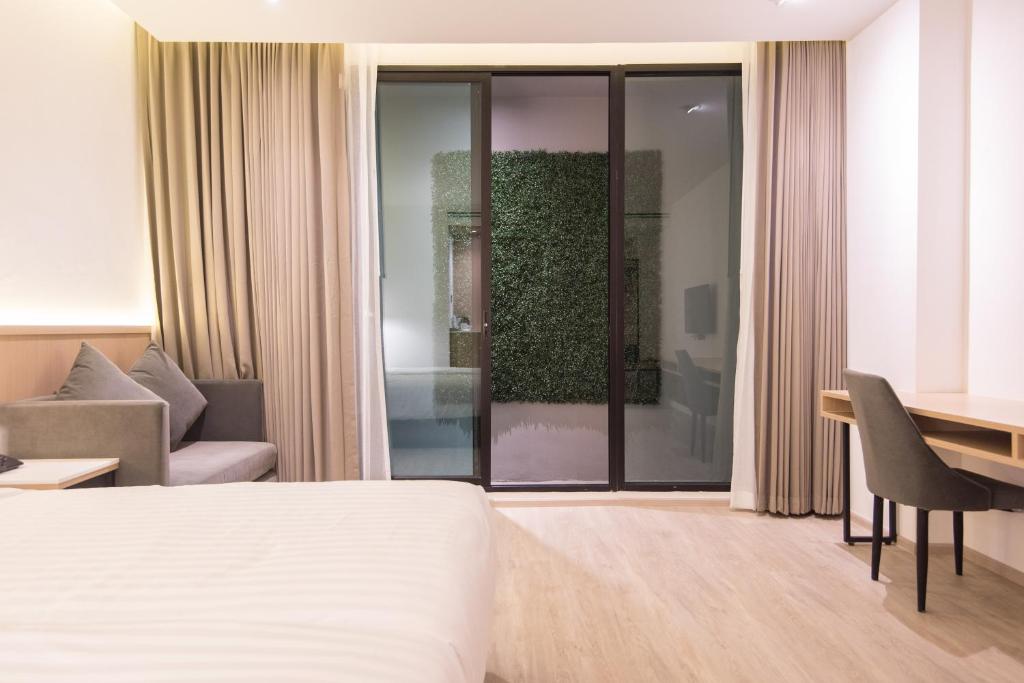 A bedroom view showing the bed, sofa, glass doors and dedicated desk.