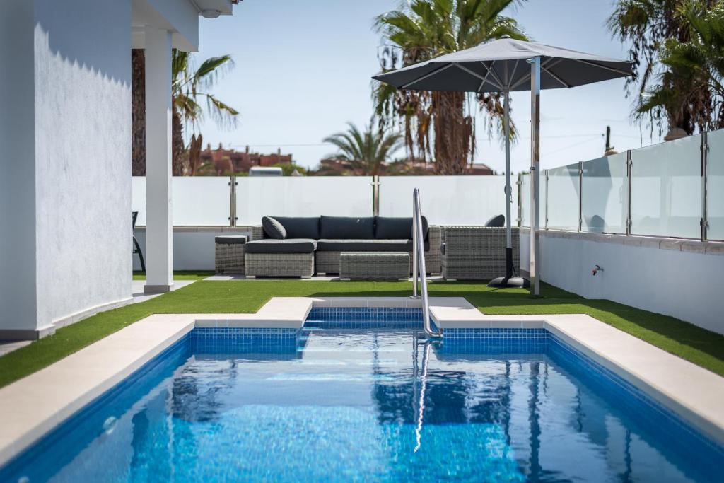 a swimming pool with an umbrella and a couch at Luxurious 5* VILLA - 300M2 - private HEATED pool - garage - WiFi in Palm-mar