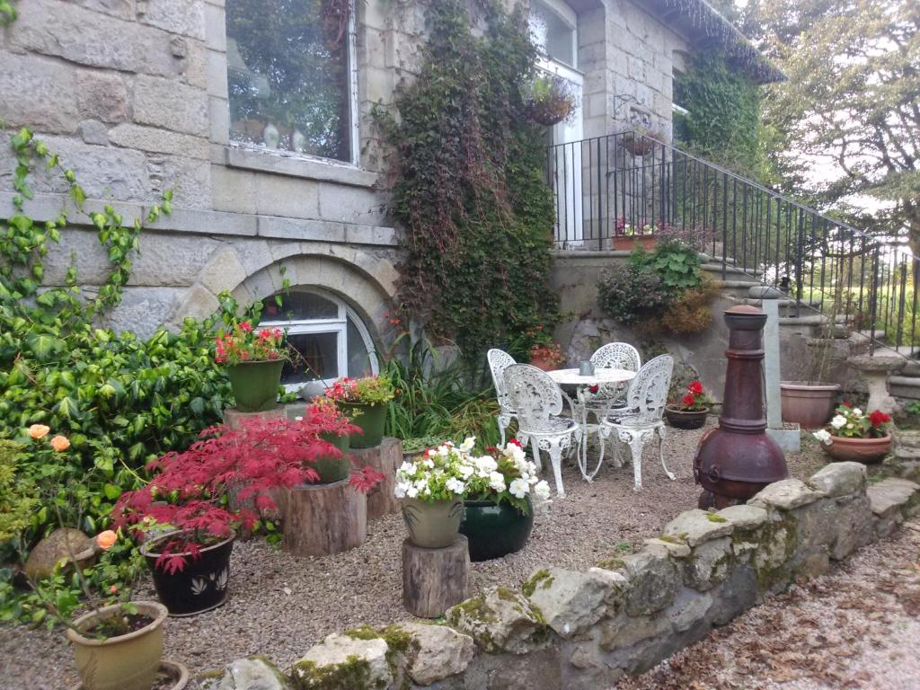 een tuin met een tafel, stoelen en bloemen bij Disblair House in Newmacher