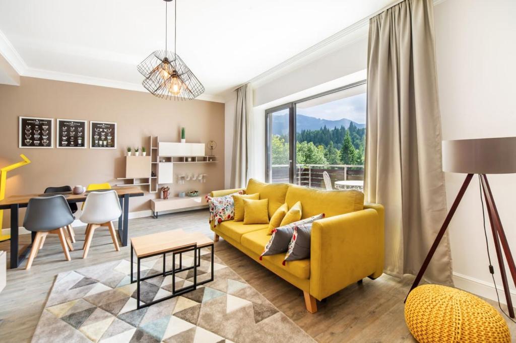 a living room with a yellow couch and a table at Sarah Deluxe Apartment in SILVER MOUNTAIN in Poiana Brasov