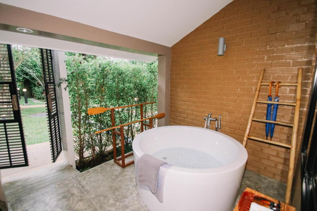 a bath tub in a bathroom with a large window at Deevana Krabi Resort in Ao Nang Beach