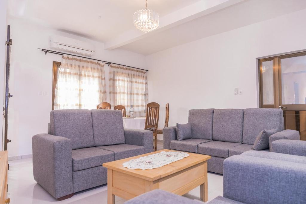 un soggiorno con 2 sedie, un divano e un tavolo di Appartement F4 Climatisé RDC à Totsi près de la maison ADEBAYOR a Lomé