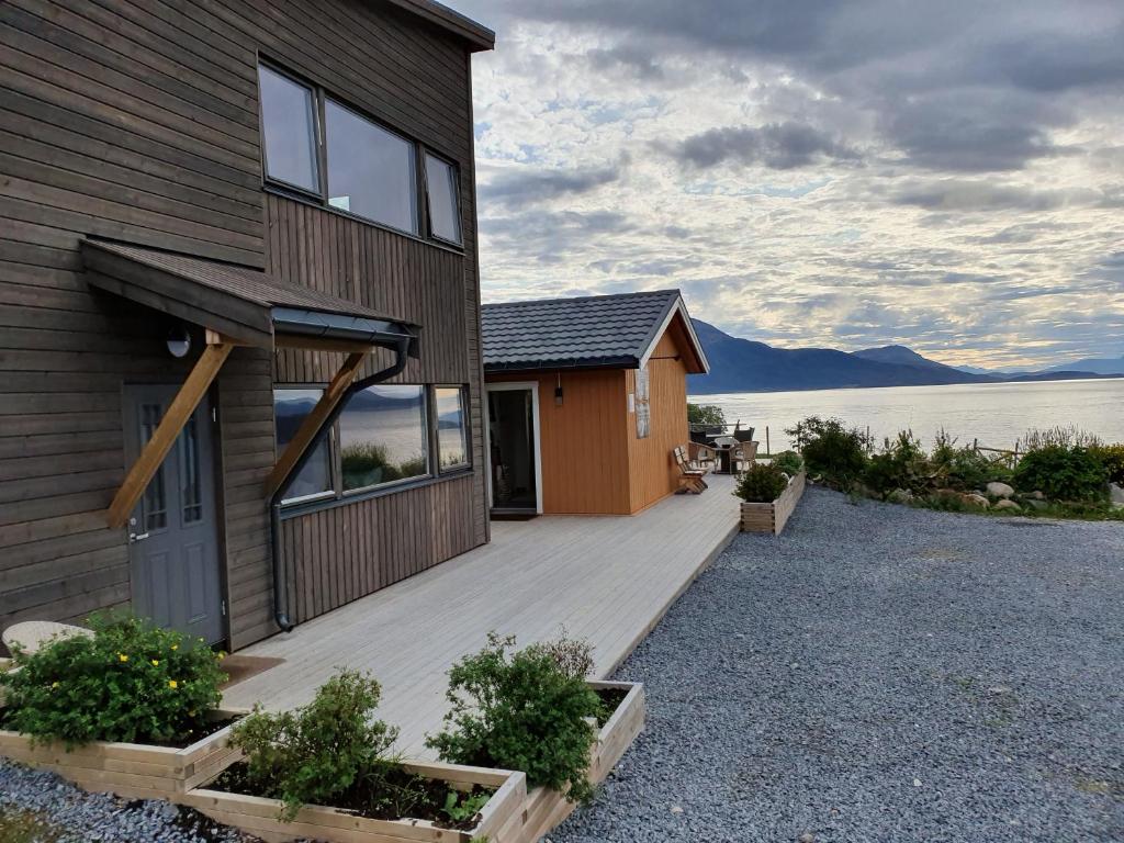 a house with a wooden deck next to the water at Yggdrasil farmhotel retreat & spa in Straumsbukta