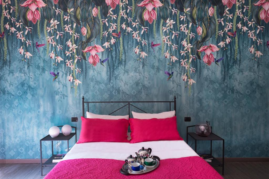 a bedroom with a bed with red pillows and a floral wallpaper at BOTANIKA in Bologna