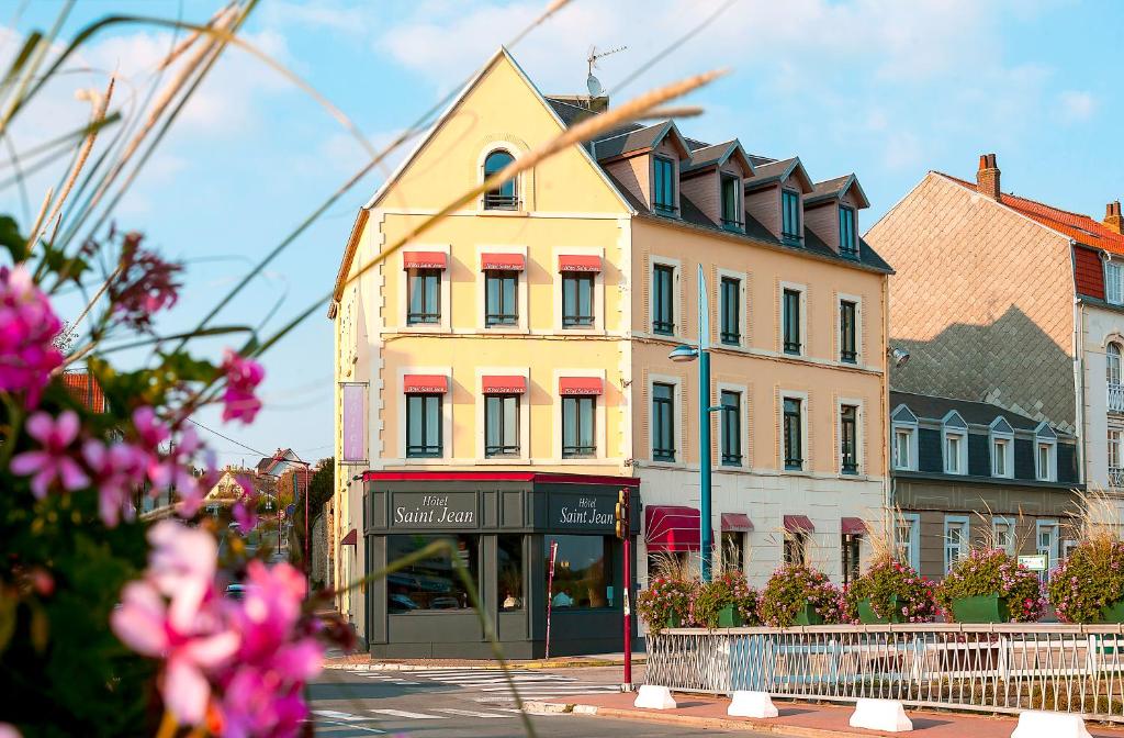 um edifício amarelo numa rua da cidade com flores cor-de-rosa em Saint Jean em Wimereux