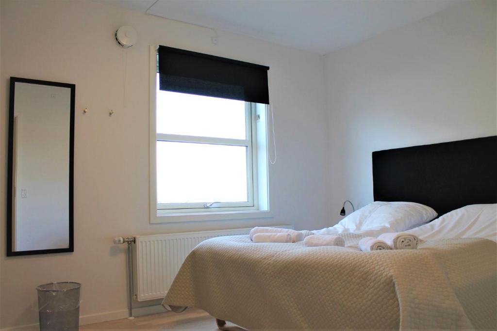 a bedroom with a bed with white sheets and a window at Hotel Nuka in Ilulissat