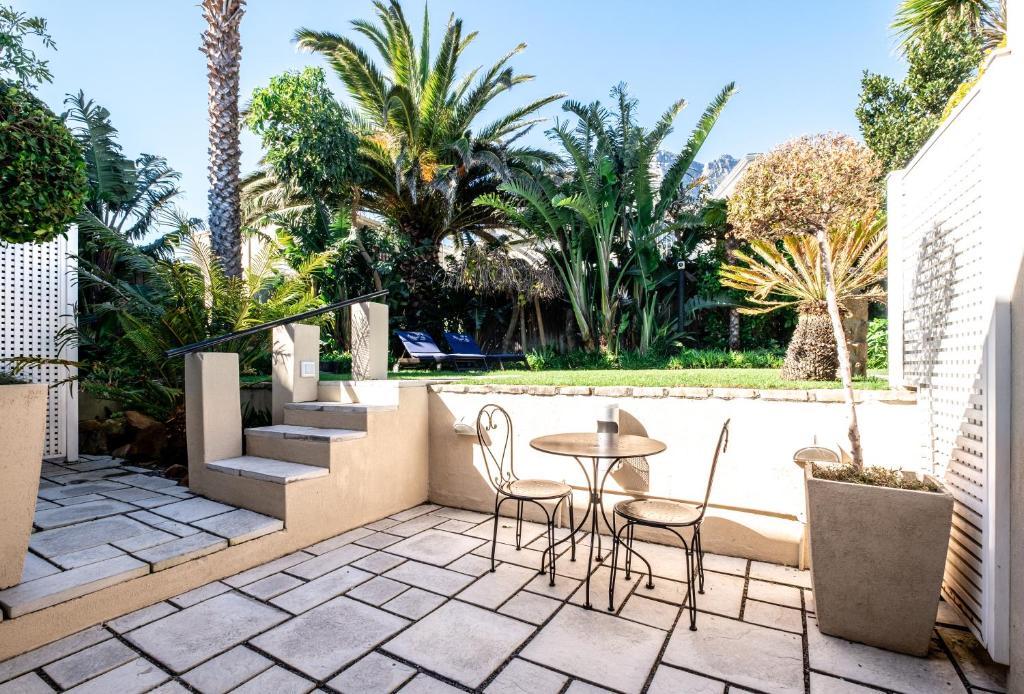 a patio with a table and chairs and palm trees at 3 On Camps Bay in Cape Town