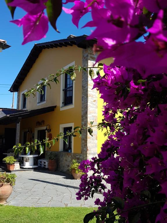 una casa con flores púrpuras delante de ella en Apartamentos Rurales Casa Pachona, en Puerto de Vega