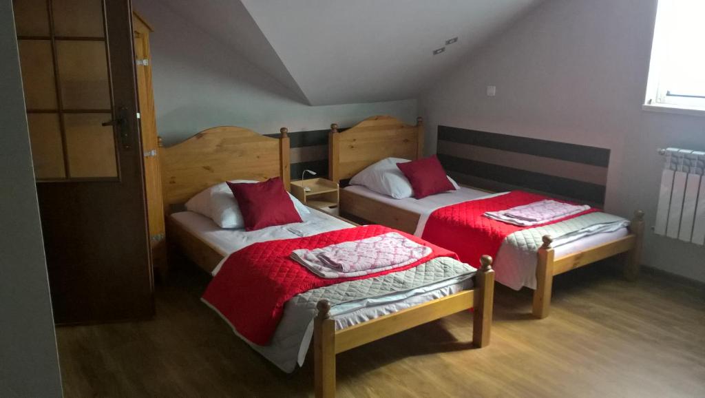 a bedroom with two beds with red sheets at Agroturystyka Nowogród in Nowogród