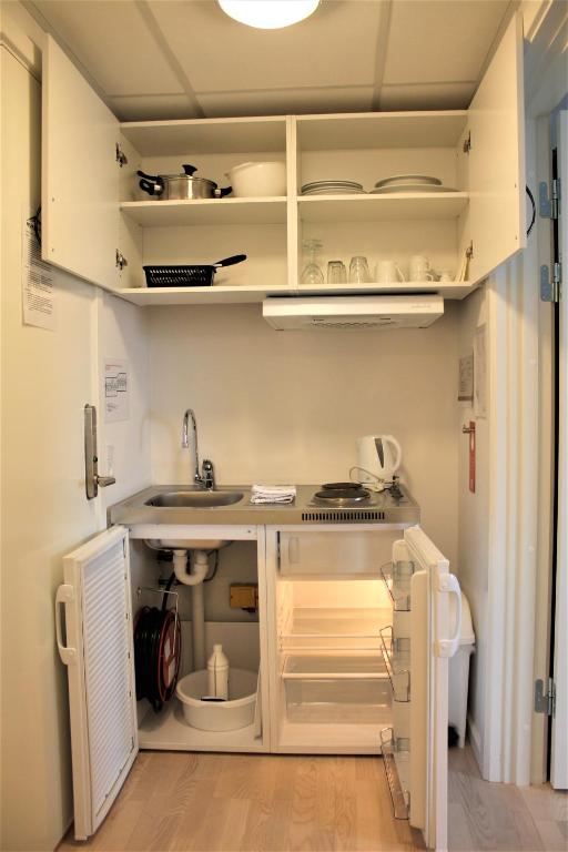 a kitchen with a sink and an open refrigerator at Hotel Nuka in Ilulissat