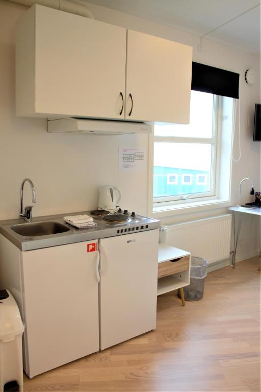a kitchen with white cabinets and a sink at Hotel Nuka in Ilulissat