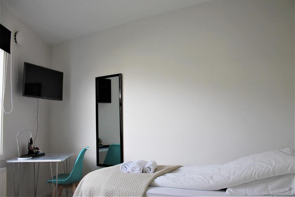 a white bedroom with a bed and a mirror at Hotel Nuka in Ilulissat