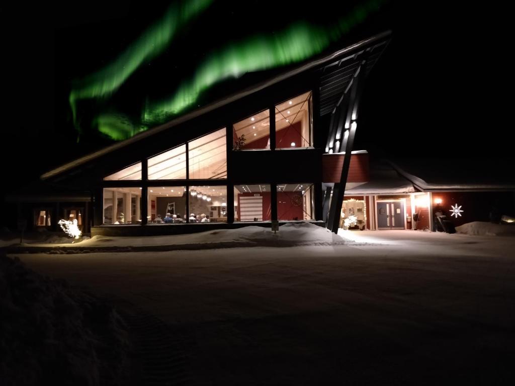a building with green lights in the snow at night at Hotel Seita in Äkäslompolo