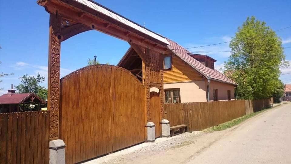 une clôture en bois devant une maison dans l'établissement Emília vendégház, à Ciumani