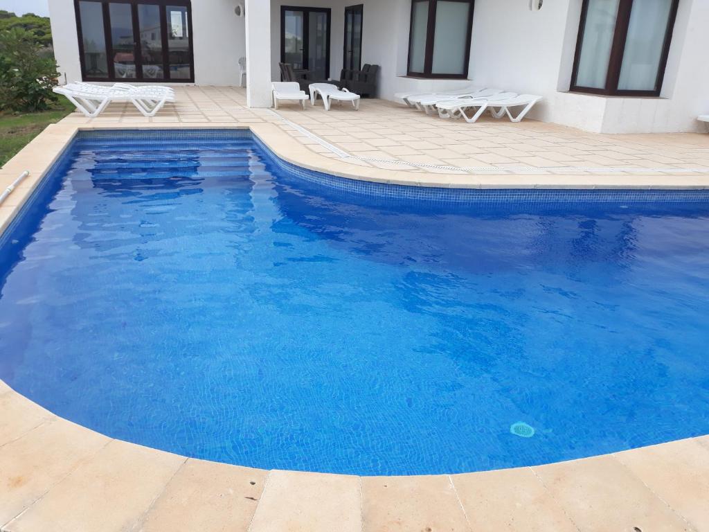 una gran piscina azul junto a una casa en Villa Elegante, en Cala Morell