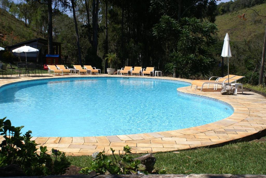a large swimming pool with chairs and a table at Hotel Fazenda São Francisco in Cunha