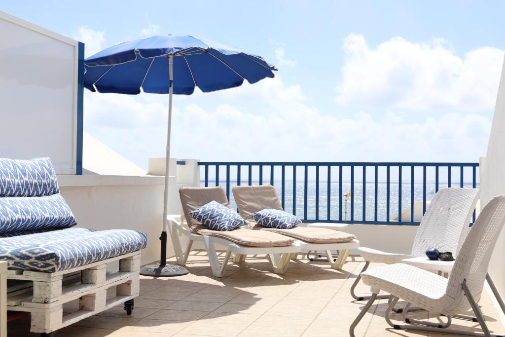 a patio with chairs and an umbrella on a balcony at Sunrise Casita del Mar in Arrieta