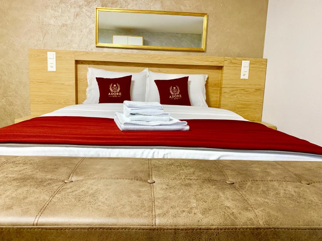 a bedroom with a bed with red sheets and red pillows at Hotel Adore in Romanel-sur-Lausanne