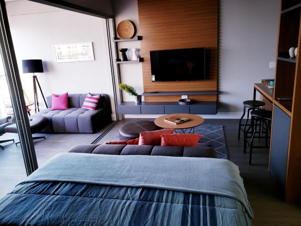 een slaapkamer met een bed en een woonkamer bij Moderno Oca Moema in Sao Paulo