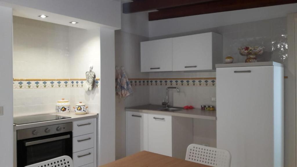 cocina con armarios blancos y nevera blanca en ALLOGGI DEL SOLE, en Polignano a Mare