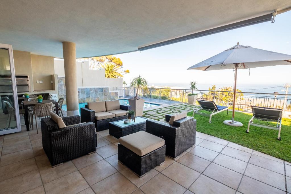 a living room with chairs and an umbrella and a patio at 3 On Camps Bay in Cape Town