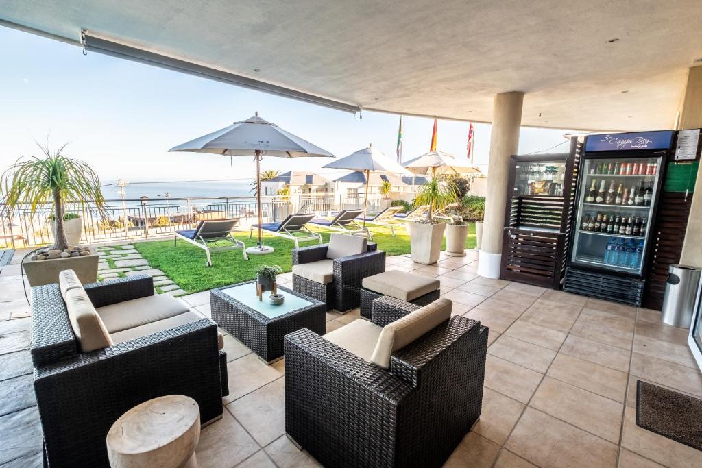 a patio with couches and tables and a view of the ocean at 3 On Camps Bay in Cape Town
